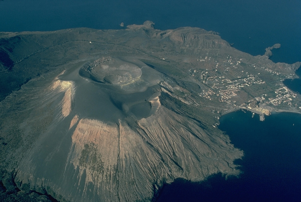 Fossa volcano, at the northern end of the island of Vulcano, has been active throughout the Holocene, and has been the source of most of the historical eruptions of Vulcano.  Fossa is a composite volcano that was constructed within the 3-km-wide Caldera della Fossa (whose rim is visible at the upper right), the northernmost of a series of three overlapping calderas on the island.  The summit crater of Fossa, seen here from the SE, is 500 m wide and about 100 m deep. Copyrighted photo by Katia and Maurice Krafft, 1982.