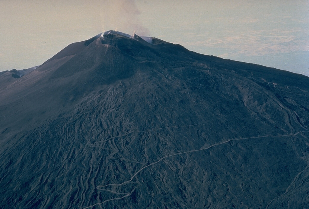 Three large craters cap the summit of Mount Etna, the NE Crater, the Central Crater, and the SE Crater.  Long-term minor eruptions occur from the NE and Central craters, and to a lesser extent from the SE Crater, which formed in 1978.  Pyroclastic ejecta mantles the upper flanks of the summit cones, and lava flows furrow the lower flanks. Copyrighted photo by Katia and Maurice Krafft.