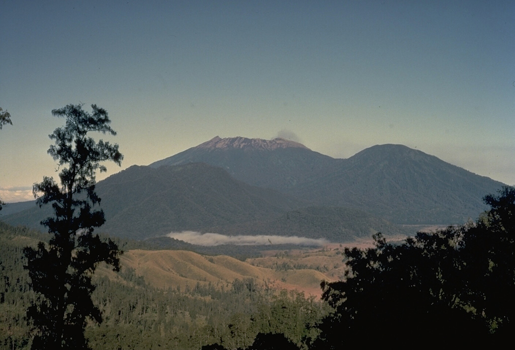 The summit of the massive Raung volcano, part of a group of volcanoes along a NW-SE-trending line near the eastern tip of Java, is truncated by a steep-walled, 2-km-wide caldera.  This view from Ijen caldera NW of Raung shows Raung at the center and Gunung Suket on the right.  Raung is one of Java's most active volcanoes,  producing frequent explosive eruptions from a central cone within the caldera. Copyrighted photo by Katia and Maurice Krafft, 1971.