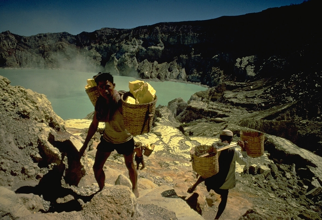 Kawah Ijen crater within the Ijen caldera is noted for its deposits of sulfur.  Large blocks of the elementally pure sulfur are broken off with hammers and carried laboriously out of the crater in baskets before being transported to a sulfur mill on the SE flank of the caldera. Copyrighted photo by Katia and Maurice Krafft, 1971.