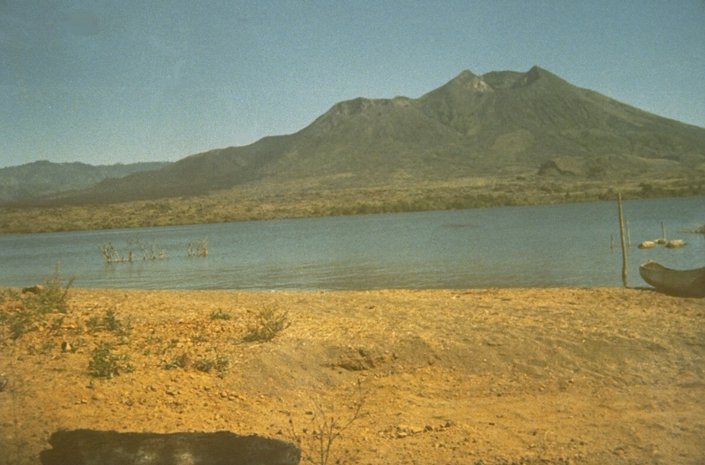 The Batur cone on the island of Bali was constructed as a result of eruptions along a NE-SW-trending line of vents. It is located within a 7.5-km-wide inner caldera with its SE margin below a lake that fills part of the SE floor of an outer 10 x 13 km caldera. Historical lava flows have formed much of the far lake shore in this view. Photo by Sumarna Hamidi, 1973 (Volcanological Survey of Indonesia).