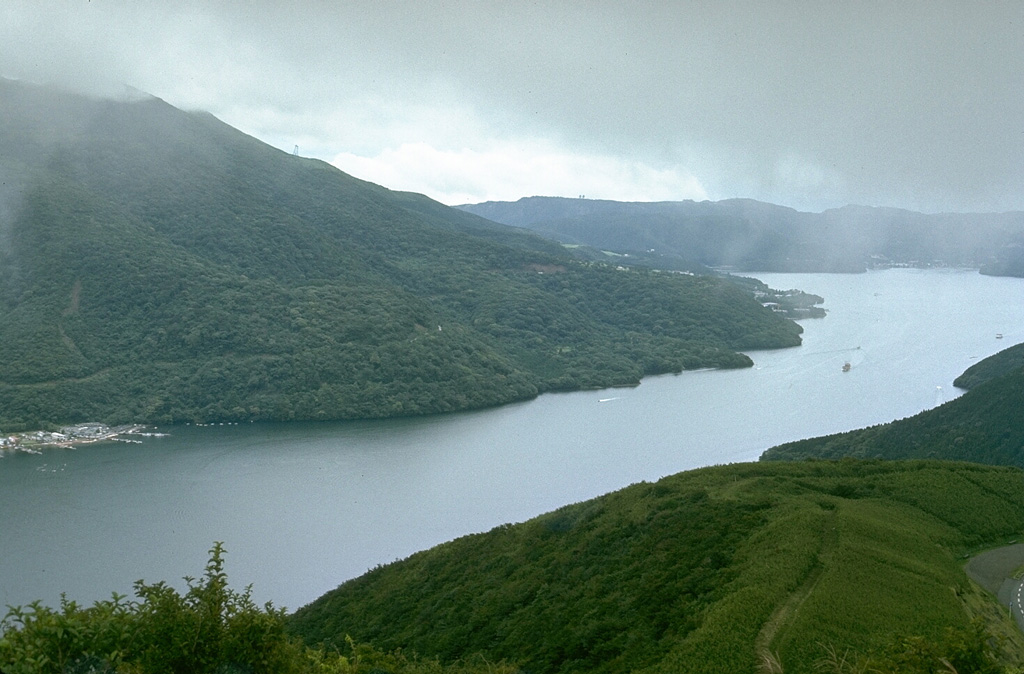 The flanks of a group of post-caldera lava domes are to the left above Lake Ashi in SW Hakone caldera. Lake Ashi formed when an avalanche from Kamiyama, the highest of the central lava domes, blocked river valleys that drain to the E through a breach in the caldera wall. Photo by Lee Siebert, 1977 (Smithsonian Institution).