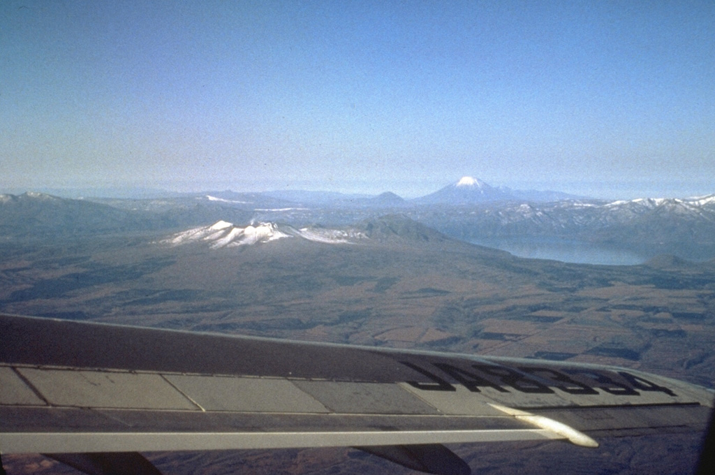 Shikotsu caldera, seen from the SE with Yoteizan volcano on the horizon, is a 13 x 15 km caldera filled by Lake Shikotsu. Following formation of the caldera more than 30,000 years ago, three small cones were constructed along a NW-trend across the caldera. Snow-capped Tarumai (left center) formed near the SE rim of the caldera, along with Fuppushi to its right. A third volcano, Eniwa, was constructed on the NW caldera rim at the far side of the lake. Photo by Ichio Moriya (Kanazawa University).