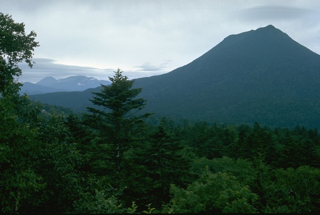 Oakandake, the peak to the right, is the largest of a group of cones constructed within the 13 x 24 km Akan caldera. It is seen here from the E with the Meakan volcano group that occupies the opposite SW side of the caldera, on the distant left horizon. Akan Caldera is the southernmost of a group of three large calderas in NE Hokkaido. Photo by Lee Siebert, 1977 (Smithsonian Institution).