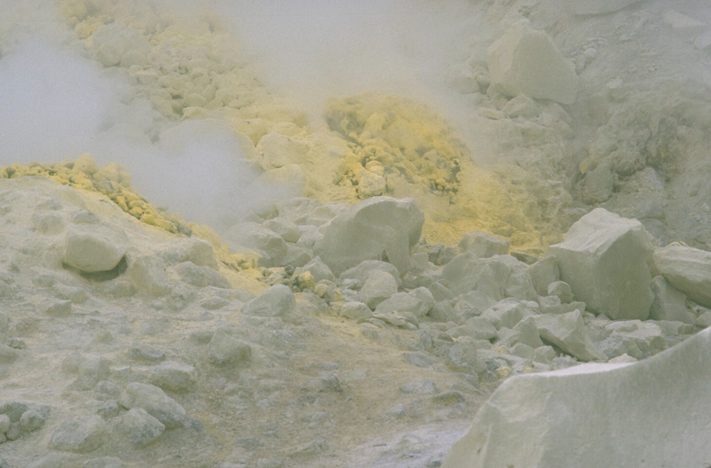 Intense fumarolic activity occurs on the margins of Atosanupuri lava dome and from fissures along the dome. Constant high-temperature emission of steam and gas has extensively altered the dome rock. Areas of sulfur deposition such as this are common and have been mined since 1887. Photo by Lee Siebert, 1977 (Smithsonian Institution).