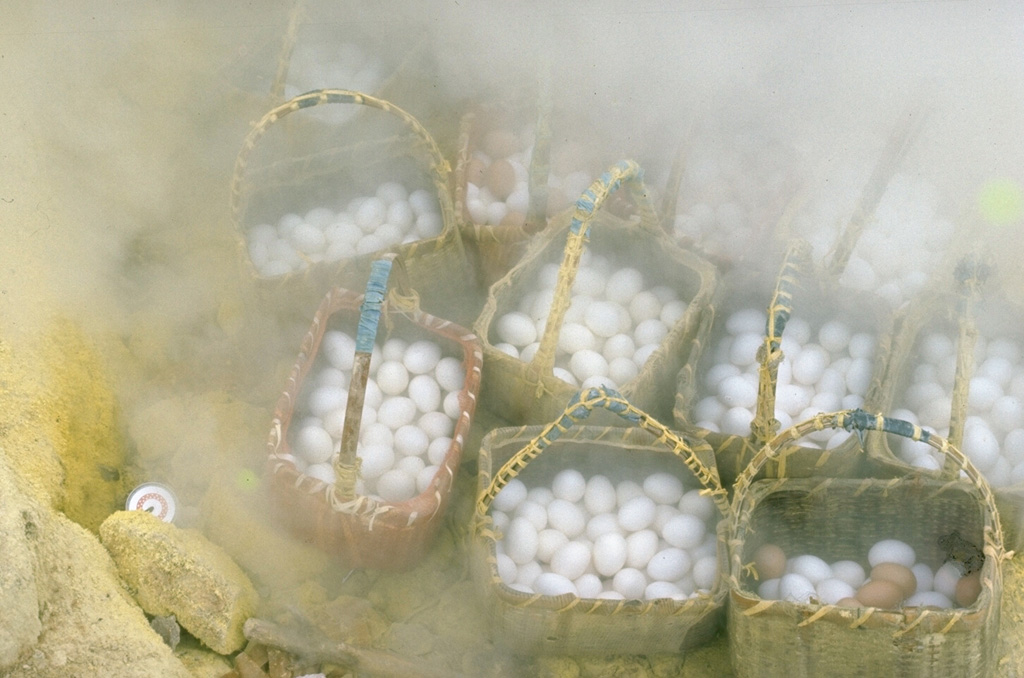 Souvenir vendors at Atosanupuri volcano take advantage of fumarolic activity to cook baskets of hard-boiled eggs for visiting tourists. Atosanupuri is the youngest of a group of lava domes on the E side of Kussharo Caldera.  Geothermal areas are common on the margins of the dome and radial fissures. Photo by Lee Siebert, 1977 (Smithsonian Institution).