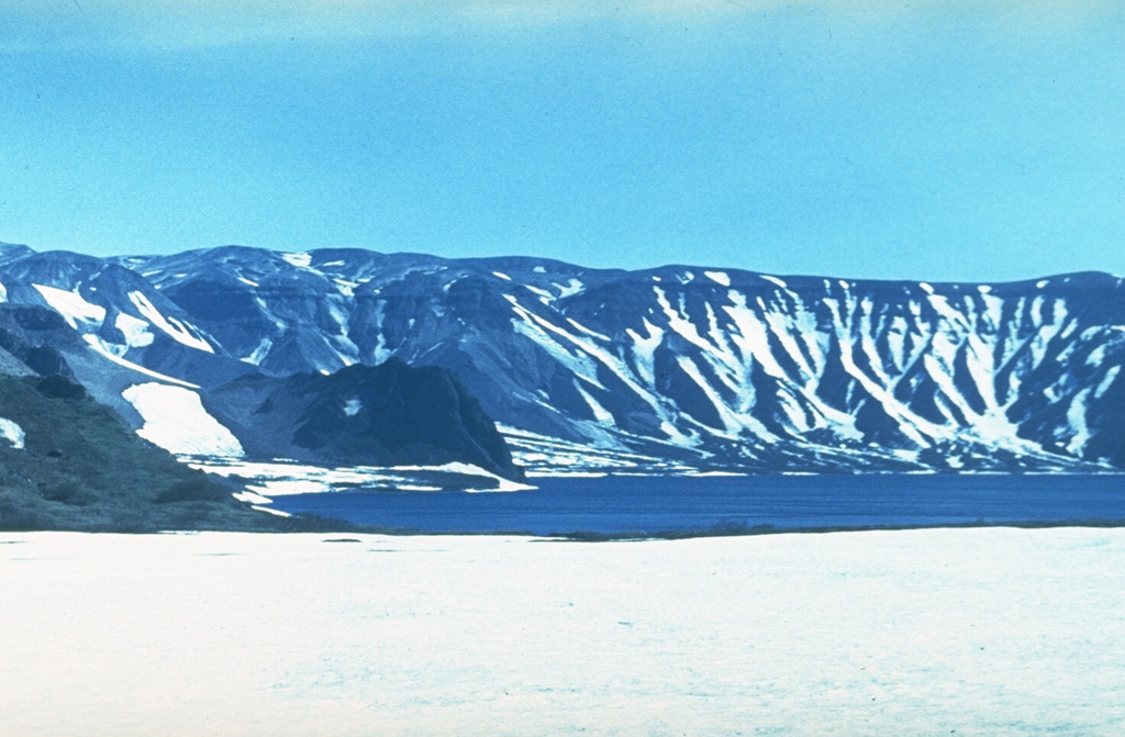 Lake Kluchevoe occupies the Ksudach IV caldera, which was formed during major explosive eruptions about 6,000 years ago. This view looks across the caldera lake to the southern caldera wall. The caldera rim forms the right-hand horizon. The caldera wall in this photo consists of two caldera rims, Ksudach IV to the right, and the late-Pleistocene Ksudach II caldera rim to the left. The Zamok lava dome is across the lake to the left-center. Photo by Andrei Tvsestov.