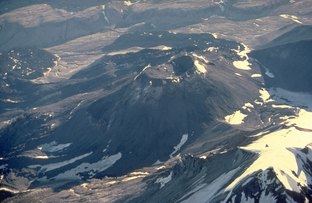 The prominent cone in the center of the photo was constructed during a series of eruptions from 1953 to 1968.  Following the emission of four lobate lava flows from 1953 to 1960 that traveled up to 4.5 km from the vent, the cone grew to heights of 400-800 m above the sloping SW flank of Trident.  A shallow, 250-m-wide crater caps the cone. Copyrighted photo by Katia and Maurice Krafft, 1978.