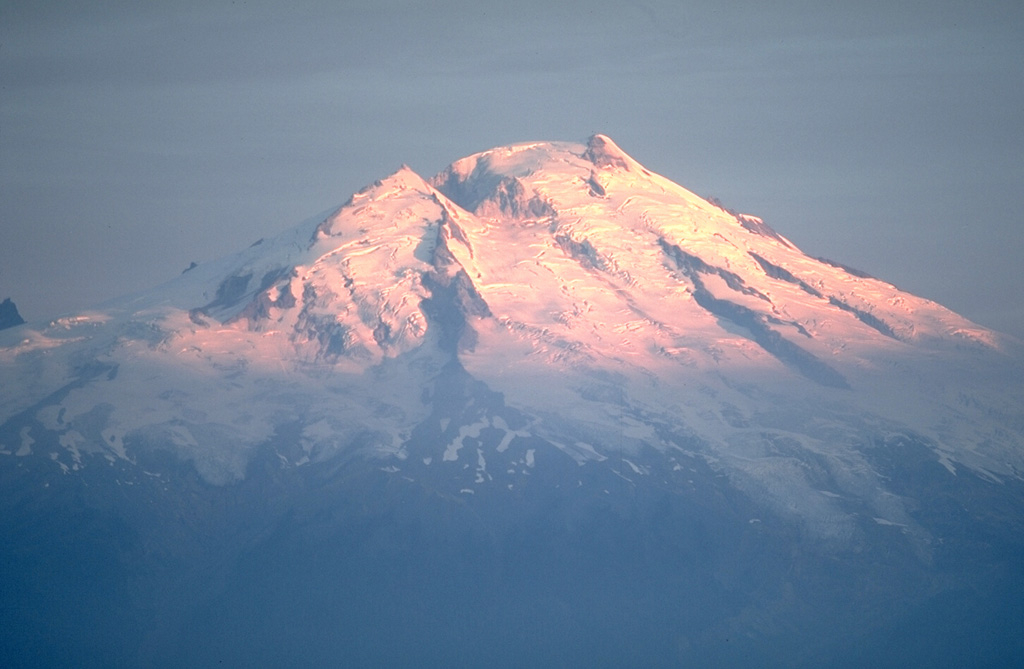 The glaciated Mount Baker is the northernmost of Washington's active volcanoes in the northern Cascade Range, seen here from the SE above Baker Lake. Historical eruptions have originated from Sherman Crater to the left of the summit. Minor phreatic explosions were observed during the 19th century by early settlers in the Puget Sound area as far away as Victoria, British Columbia. Photo by Lee Siebert, 1981 (Smithsonian Institution).