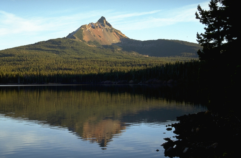 Mount Washington, reflected here in Big Lake on its NW side, is a Pleistocene shield volcano deeply dissected by glaciers.  Erosion has exposed many dikes in the summit cone, which has not erupted since the late Pleistocene.  Vents on the NE flank, behind the ridge on the left, erupted about 1300 years ago, probably as part of a a fissure-fed eruption at Blue Lake Crater. Photo by Lee Siebert, 1995 (Smithsonian Institution).