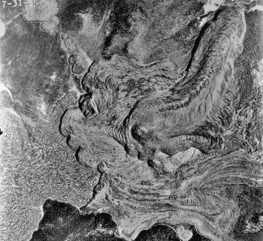 This aerial photo shows the lobate morphology of the Glass Mountain obsidian flow, which erupted around 950 years ago from a series of vents near the buried east rim of Medicine Lake caldera. The eruption originated from a series of NW-SE-trending vents, seen here diagonally across the photo from the upper left. Three dacite flows to the east are overlain by rhyolite flows towards the west. The flow at  lower left is the dacitic Hoffman flow, erupted only a few hundred years prior to the Glass Mountain flow.  Photo by U.S. Geological Survey (published in Green and Short, 1971).