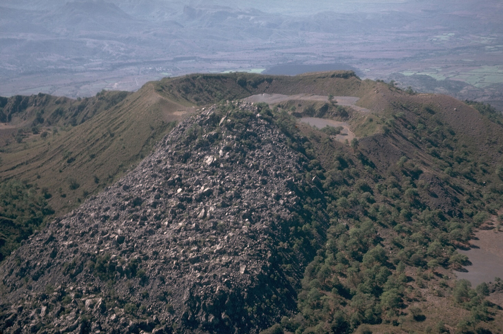 A small lava flow, possibly produced during or before the 1870-75 eruption of Ceboruco, descended eastward from the rim of a crater within the inner caldera. This flow traveled 500 m to the east. The small crater to the right of the flow formed in the NE side of the larger crater. These are part of a complex group of features within the nested summit calderas. Photo by Jim Luhr, 1980 (Smithsonian Institution).