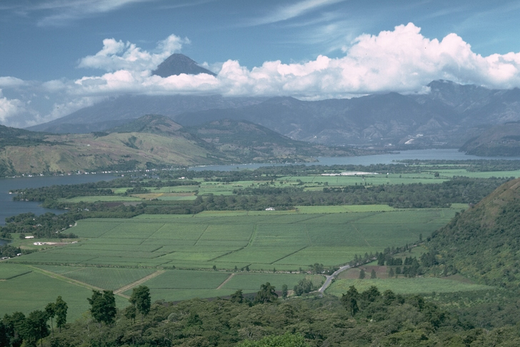 Volcán de Agua (left) rises above the clouds west of Lake Amatitlán, located within the Amatitlán caldera. This 14 x 16 km Pleistocene caldera has produced many large explosive eruptions whose deposits underlie Guatemala City and surrounding areas. Pacaya volcano, out of view to the left, was constructed over the buried southern rim of Amatitlán caldera.  Photo by Lee Siebert, 1988 (Smithsonian Institution).