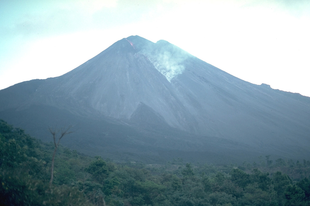 An ash plume generated by collapse of a lava flow front is seen on the SW flank of Pacaya in November 1988. Frequent Strombolian eruptions began at MacKenney cone in 1965 and were often accompanied by lava flows from summit or flank vents, which have traveled out to 6 km down the southern flank. Photo by Lee Siebert, 1988 (Smithsonian Institution).