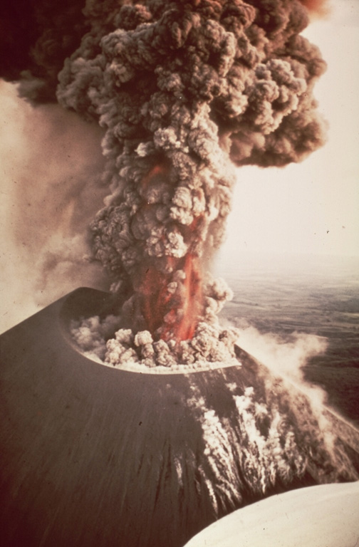 An eruption from Nicaragua's Cerro Negro volcano in 1968 produces an ash plume above the vent. Incandescent ejecta is visible at the base of the column. Gas and steam rise from fumaroles on the righthand side of the scoria cone. Ash and bombs fall from the eruption column at the left. Photo by William Melson, 1968 (Smithsonian Institution).