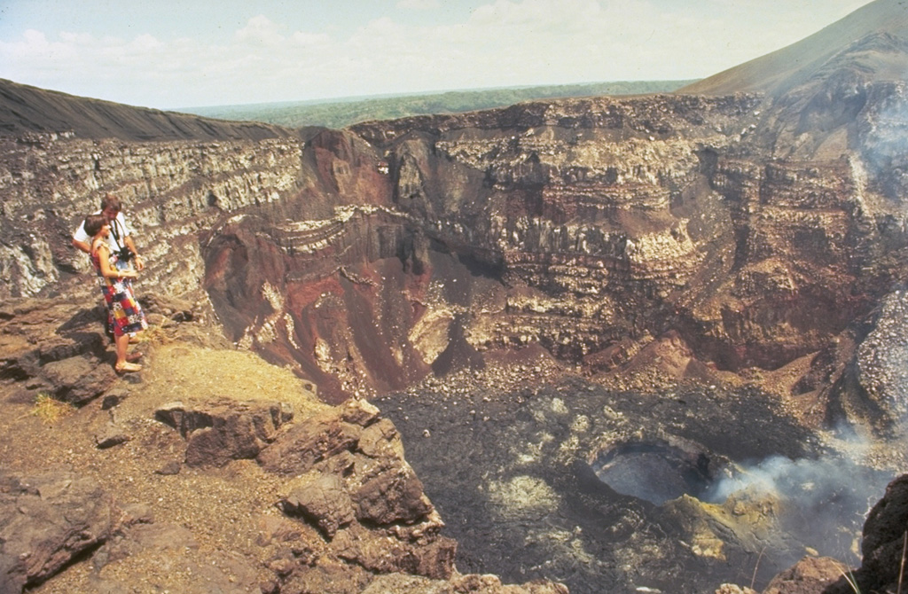 Steep-walled Santiago crater provides a dramatic perspective into the vent of an active volcano.  The crater floor is covered by recent lava flows and fume rises from an inner crater.  The walls of the 600-m-wide crater expose stacked lava flows, truncated lava lakes, and pyroclastic material erupted from earlier vents.  Photo by Jaime Incer.