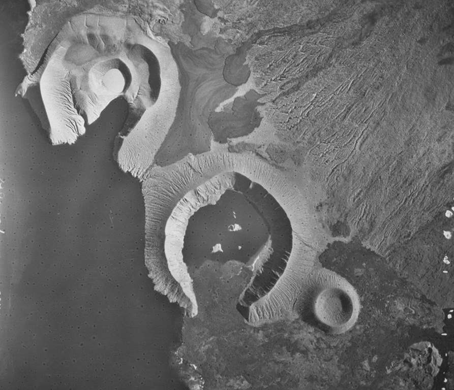 The tuff cones of Tagus (upper left) and Beagle (lower right) were formed by phreatomagmatic eruptions at Darwin volcano in the Galápagos Islands. The rim of Tagus is breached by Tagus Cove that was visited by Charles Darwin's vessel, the Beagle. Tagus tuff cone has at least four nested craters, the youngest of which contains a small salt lake. Young black lava flows from fissures on the flanks largely surround the tuff cones. Aerial photo by U.S. Air Force.