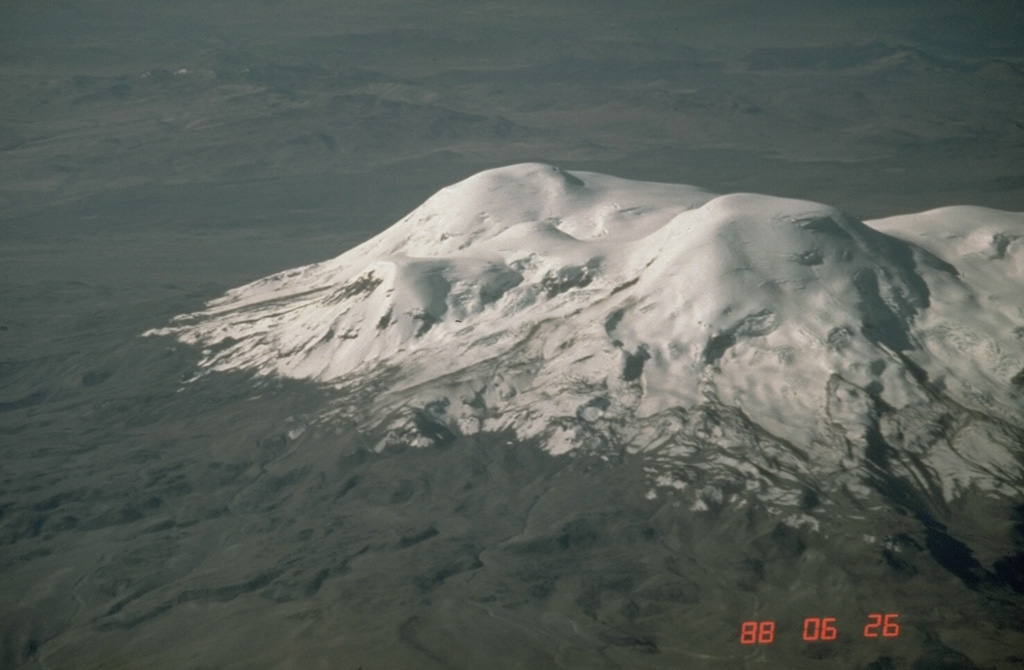 The 6377-m-high summit of Coropuna volcano, Perú's highest, forms the peak at the center of the photo.  It lies north of a 20-km-long E-W chain of peaks forming the ice-covered massif.  The present glacial icecap covers an area of 130 km2 and descends to 5800 m on the south and 5300 m on the north.  Dramatic lateral moraines from older glaciers extend up to 10 km and reach below 4500 m.  Steep canyons on the volcano's flanks create among the world's highest topographic relief, up to 4000 m over a horizontal distance of 15 km. Photo by Norm Banks, 1988 (U.S. Geological Survey).