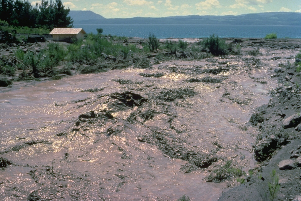 A lahar from Villarrica volcano in the Chilean lake district sweeps down the Correntoso river into Lake Villarrica in December 1984.  The lahar flattened a small wooden bridge and affected houses on the banks of the river.  The mudflow originated when the rate of effusion of a lava flow moving down the glacier-covered flanks of the volcano increased during the afternoon of December 6.  By the following day stream flow had returned to normal. Copyrighted photo by Katia and Maurice Krafft, 1984.