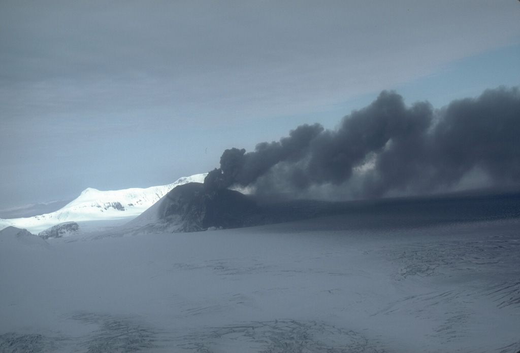 This weak, pulsating ash plume at Veniaminof, Alaska, on 7 October 1983 is being directed to the east by local winds. Dark ash deposits are visible on the cone and glacier, and a lava flow was traveling down the flank. Photo by Betsy Yount, 1983 (Alaska Volcano Observatory, U.S. Geological Survey).