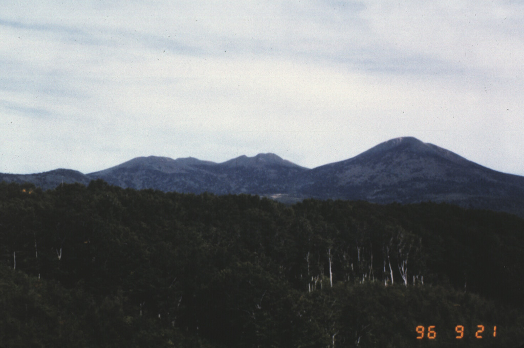 Hakkoda consists of a group of 14 cones and lava domes south of Mutsu Bay at the northern end of Honshu. The NE rim of an 8-km-wide Pleistocene caldera forms an arcuate ridge across the caldera floor to the NE of the Hakkoda group volcanoes, which bury the SE caldera wall. This view looks from the W towards the northern Akakuradake, Idodake, and Hakkodasan volcanoes seen from left to right.  Photo by Takashi Kudo, 1996 (Hokkaido University).