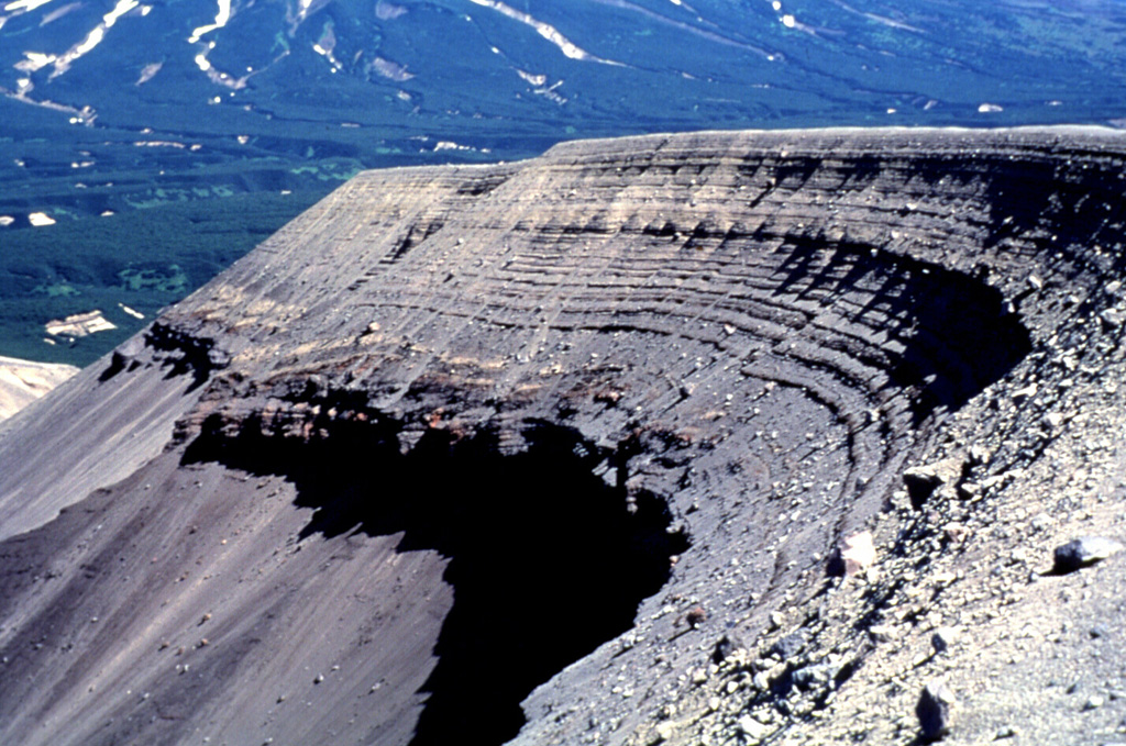 The bedded layers in this photo are tephra fall and pyroclastic surge deposits produced by successive explosions during the formation of a maar on the NE flank of Iliinsky in 1901. This eruption created a new crater 800 x 1,000 m wide and 200 m deep that opens to the NE. Photo by Nikolai Smelov, 1996 (courtesy of Vera Ponomareva, Institute of Volcanic Geology and Geochemistry, Petropavlovsk).