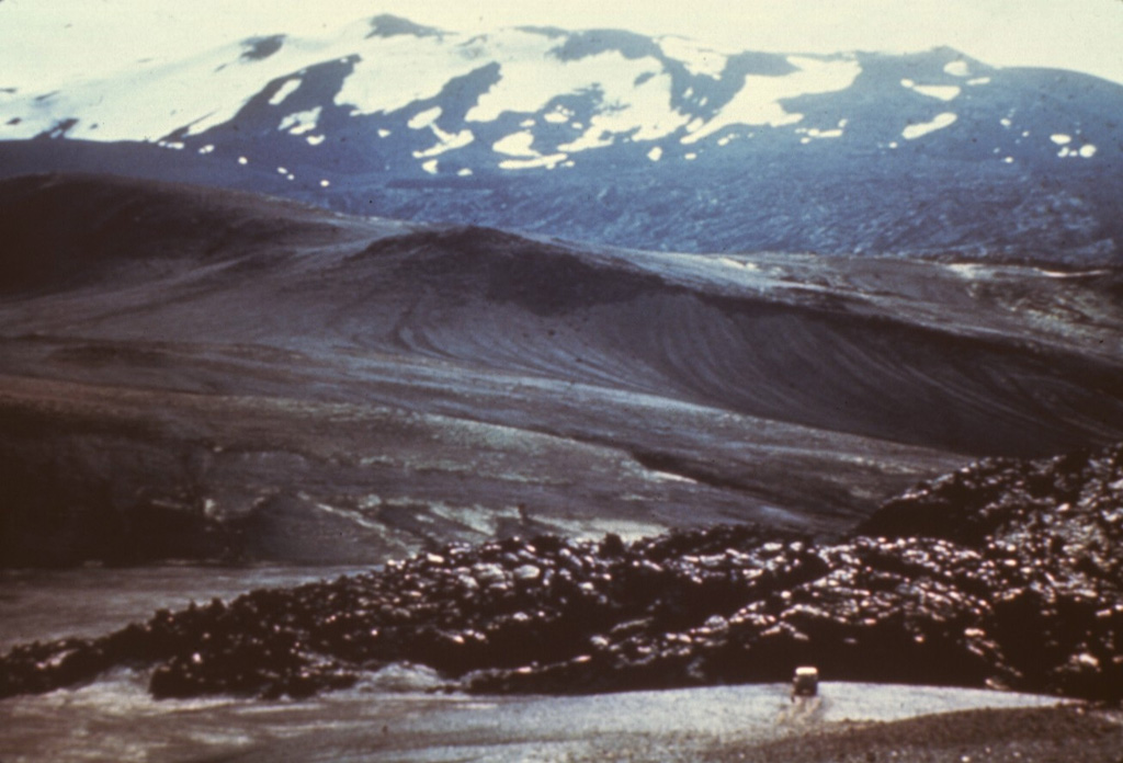 The elongated summit ridge of Hekla volcano is seen here from the west with a recent lava flow in the foreground. The 5.5-km-long Heklugja fissure cuts across the volcano and is often active along its full length during major eruptions. Repeated eruptions along this rift are responsible for Hekla's elongated ENE-WSW profile. Photo courtesy of Jules Friedman (U.S. Geological Survey).