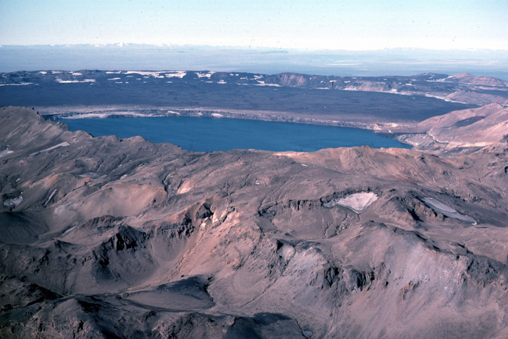 Askja is a central volcano made up of the Dyngjufjöll massif and at least three calderas, the largest of which is 8 km wide. This view from the SE looks across Öskjuvatn lake within the youngest caldera that formed in 1875 during Askja's largest historical eruption. It truncates a larger caldera, whose wall is seen in the distance above the lava-covered caldera floor. The 100-km-long Askja fissure swarm, which includes the Sveinagjá graben, is also related to the Askja volcanic system. Photo by Michael Ryan, 1984 (U.S. Geological Survey).