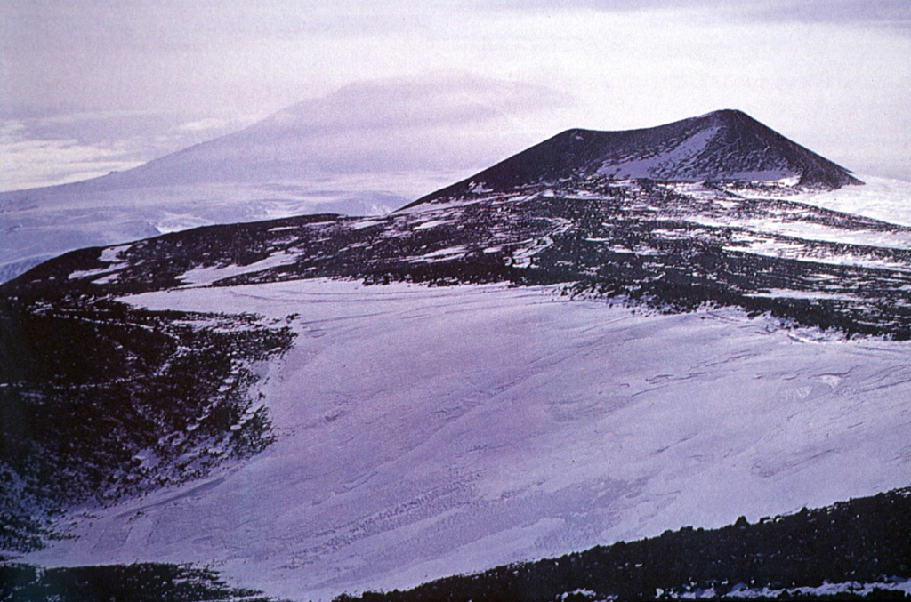 Satellitic cinder cones on the flank of Mount Waesche are composed of black, vesicular lava flows and ejected pyroclastic material of basaltic composition.  Numerous pyroclastic cones, some erupted along radial fissures, cover a broad area on the SW flank of Mount Waesche. Photo by Oscar González-Ferrán (University of Chile).