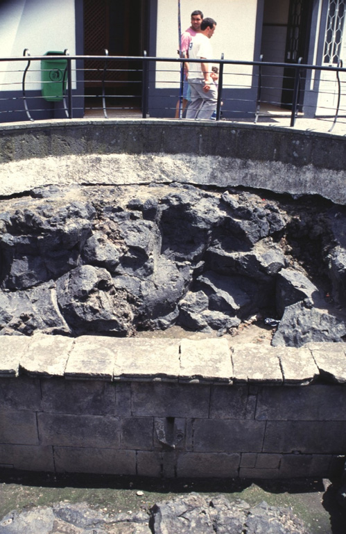 A public fountain at Ribeira Grande on the northern coast of San Miguel Island was buried by a lava flow that was erupted from Agua de Pau volcano in 1563. The lava flow originated during the Pico do Sapateiro eruption, which began on 2 July when vents formed across the Queimado dome on the NW flank, generating an eruption column with blocks and bombs. The flank eruption was preceded by a major Plinian eruption from the central caldera that began on 28 June and deposited trachytic pumice dominantly eastward over the island; the summit eruption ended a day after the flank activity began. Photo by Rick Wunderman, 1997 (Smithsonian Institution).