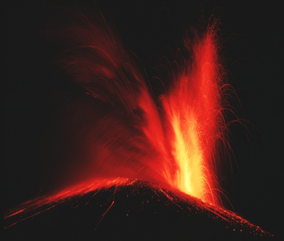 Incandescent ejecta from Cerro Negro volcano rising from a vent at the right reflects off the ash cloud to its left as glowing bombs litter the flanks of the cone.  Cerro Negro began erupting on October 23, 1968 both from the summit vent, as seen here, and from a new vent on the south flank that produced a lava flow that traveled 1.5 km.  Strong explosive eruptions damaged 700 km2 of cropland before the eruption ended on December 15. Photo by Robert Citron, 1968 (Smithsonian Institution).