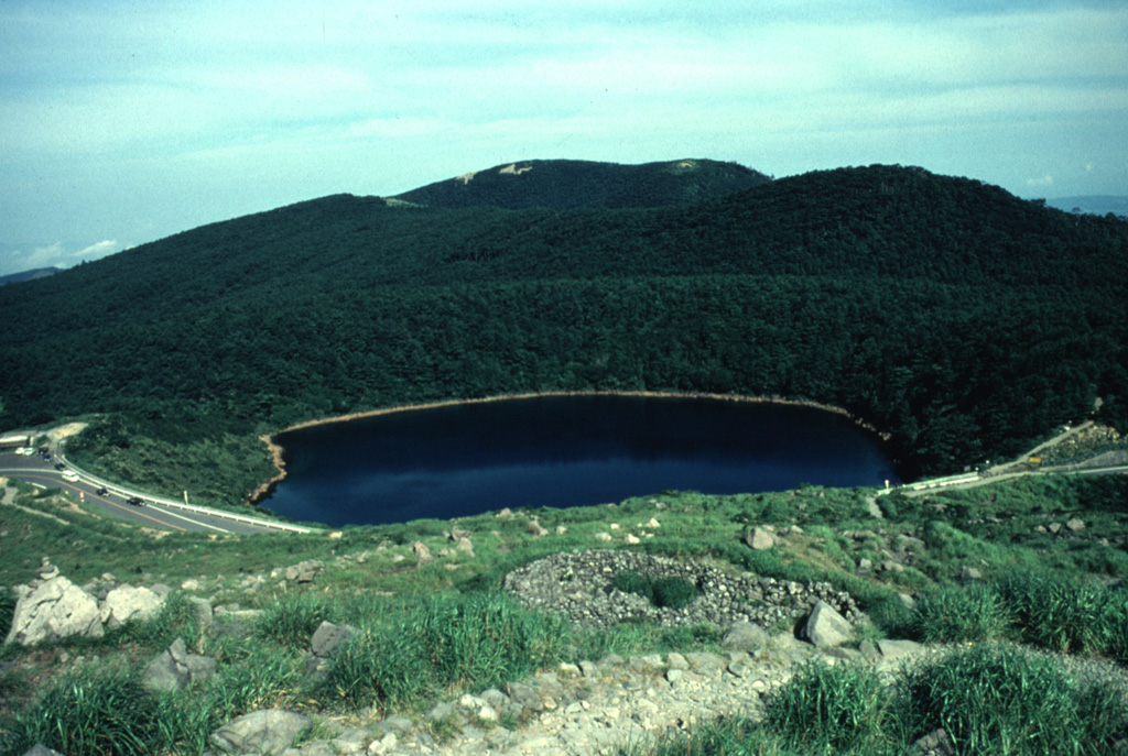 Lake-filled Rokkannon-Miike is one of several maars at Kirishima volcano, seen here with a highway along the rim. The Kirishima volcano group consists of cones, maars, and underlying shield volcanoes scattered over a 20 x 30 km area N of Kagoshima Bay. Numerous small-to-moderate explosive eruptions have been recorded at Kirishima since the 8th century. Photo by Yukio Hayakawa (Gunma University).