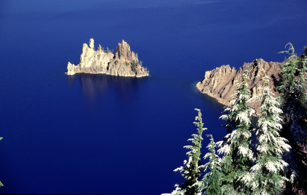 Phantom Ship is the eroded remnants of resistant dikes that now rise above the waters of Crater Lake. These dikes were feeders for lavas of Phantom Cone, the oldest of the known pre-collapse edifices forming Mount Mazama. Phantom Cone lavas have been dated to about 400,000 years before present and are exposed in the SE wall of the Crater Lake caldera. Photo by Lee Siebert, 1997 (Smithsonian Institution)