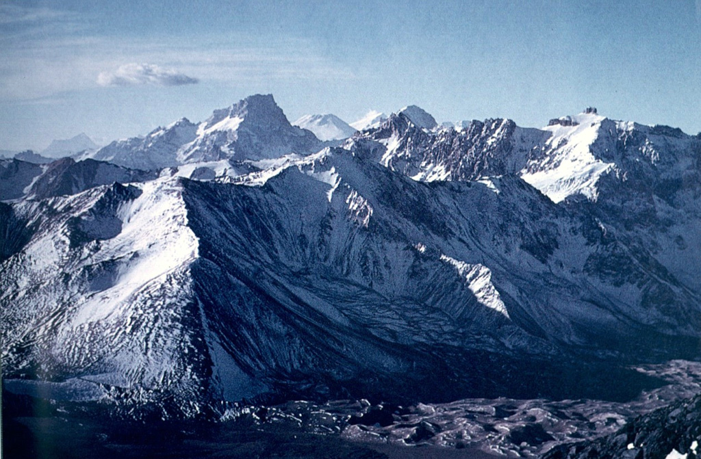 The NW rim of Diamante caldera in the center of the image rises above the caldera floor in the foreground.  The caldera was formed during voluminous rhyolitic explosive eruptions about 450,000 years ago that produced ashflows that extended radially more than 100 km from the caldera, covering much of the Central Valley of Chile and extending into Argentina.  The conical snow-capped peak on the center horizon beyond rugged intervening peaks of the Andes is San José volcano. Photo by Oscar González-Ferrán (University of Chile).