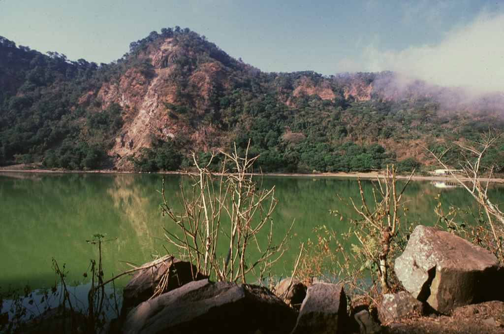 The Loma San Juan peak lies along the northern crater rim of Laguna de Alegría, a crater lake at the summit of Tecapa. Geothermal features are active along the rim of the crater lake and an area of hydrothermally altered clay containing up to 45% sulfur is found nearby. Photo by Giuseppina Kysar, 1999 (Smithsonian Institution).