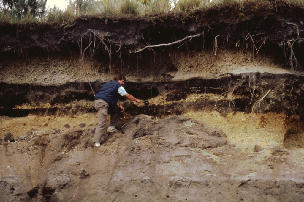 Products of three recent Plinian eruptions of Popocatépetl are seen in this stratigraphic section located near Paso de Cortés at the saddle between Popo and Iztaccíhuatl volcanoes. The thick basal unit was emplaced about 5,000 years ago. It is known as the Upper Pre-Ceramic eruptive sequence and includes pyroclastic flows and secondary lahars that traveled to the south. Volcanologist Claus Siebe is pointing to the overlying 2,500-year-old Lower Ceramic unit, and the 1,100-year-old Upper Ceramic Plinian unit lies at the top. Photo by José Macías, 1995 (Universidad Nacional Autónoma de México).