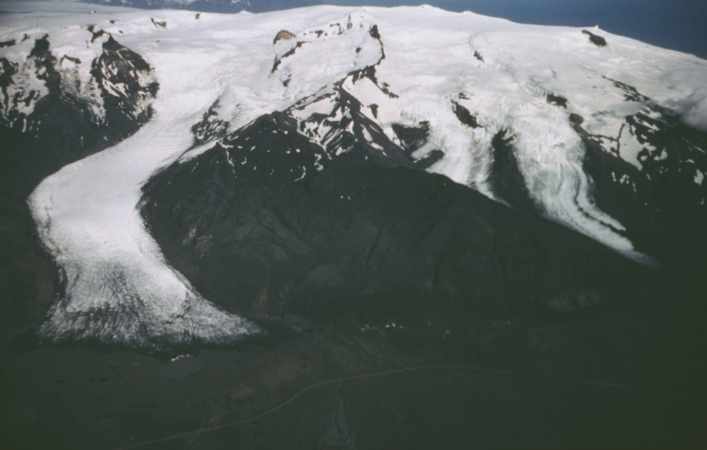 Öræfajökull is located near the SE coast of Iceland, viewed here from the west, with the Svinafellsjökull glacier (left) descending from the central icecap nearly to the coastal road. A subglacial caldera, 4 x 5 km, truncates the summit. Large eruptions in 1362 and 1727-28 were accompanied by jökulhlaups (glacier outburst floods) that caused property damage and fatalities.  Photo by Oddur Sigurdsson, 1986 (Icelandic National Energy Authority).