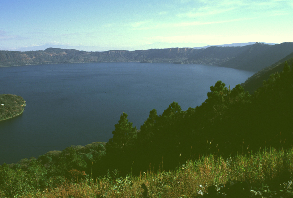 Lago de Coatepeque is within the eastern part of Coatepeque caldera, seen here from the southern caldera rim. The NE part of the caldera formed following the eruption of 40 km3 of rhyolitic pumice-fall and pyroclastic flow deposits about 72,000 years ago. The northern caldera rim in the distance rises about 250 m above the lake, which had a maximum depth of about 120 m when this photo was taken in 1999. Hot springs are located at several points along the shore of the lake near a group of post-caldera lava domes. Photo by Lee Siebert, 1999 (Smithsonian Institution).