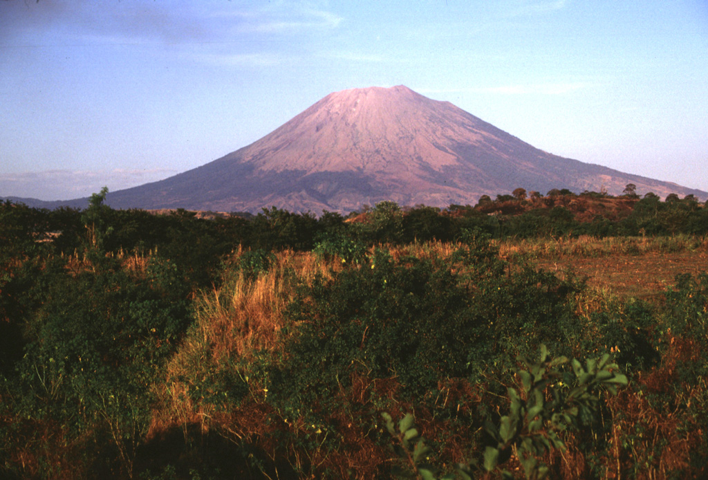 The SW side of San Miguel volcano towers more than 2000 m above the Pacific coastal plain; the base of the volcano lies only about 100 m above sea level.  The symmetrical volcano is one of the most active in El Salvador and has produced dominantly basaltic and basaltic andesite lava flows and tephra.  Frequent eruptions have kept much of the upper part of the edifice unvegetated.  Flank vents are concentrated on the SE and NW quadrants of the volcano, but have been active during historical time on all sides. Photo by Lee Siebert, 1999 (Smithsonian Institution).