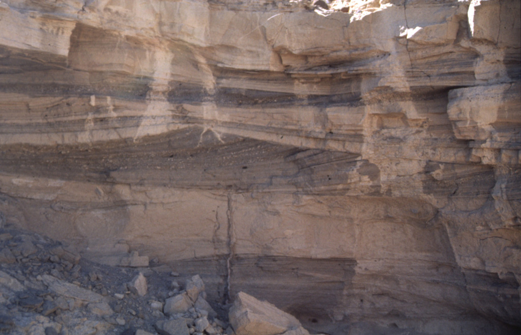 Pyroclastic surge deposits exposed in gullies on the flanks of Cráter Elegante in the Pinacate volcanic field of NW México. This photo shows cross bedding produced by particles transported by saltation or dilute suspension in a high-velocity pyroclastic surge. The direction of movement of the surge cloud, seen by the truncation of dune beds on the near-vent side, was from right to left. This type of bedding is common in areas near the rim of the maar. Photo by Bill Rose, 1997 (Michigan Technological University).