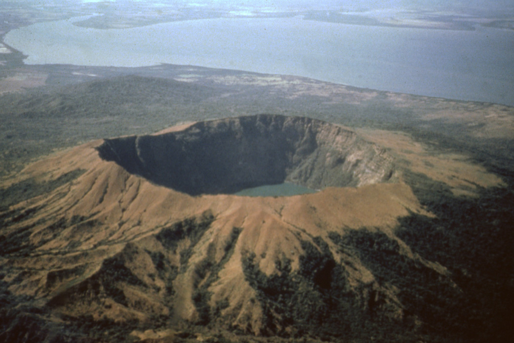 A dramatic aerial view from the NW shows Cosigüina volcano with its 2.4-km-wide caldera.  One of Central America's largest historical eruptions began on January 20, 1835.  Detonations were heard in Jamaica, Venezuela, and Colombia, and ash fell throughout Central America and southern México.  Pyroclastic flows and surges reached the Gulf of Fonseca (background), and fountain-fed lava flows mantled portions of the upper flanks.  Although the eruption devastated croplands and livestock, there were few human fatalities.  Photo by Jaime Incer, 1991.