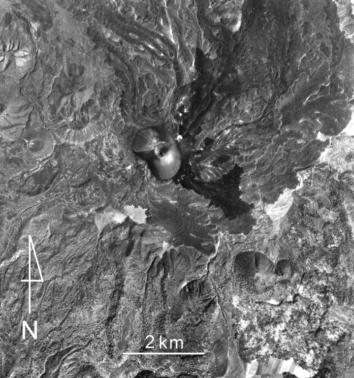 Lava flows from Parícutin (upper center) within the Michoacan-Guanajuato volcanic field cover much of the northern half of this photo. The small white dot immediately NE of the cone is the flank vent of Nuevo Juatita. The latest lava flows that formed during 1952 originated from this vent and form the darker-colored flows that extend to the SE. Cerro Tzirapan is the larger scoria cone near the center, and older cones are to the upper left. Aerial photo by Comisión de Estudios del Territorio Nacional (CETENAL), 1970.