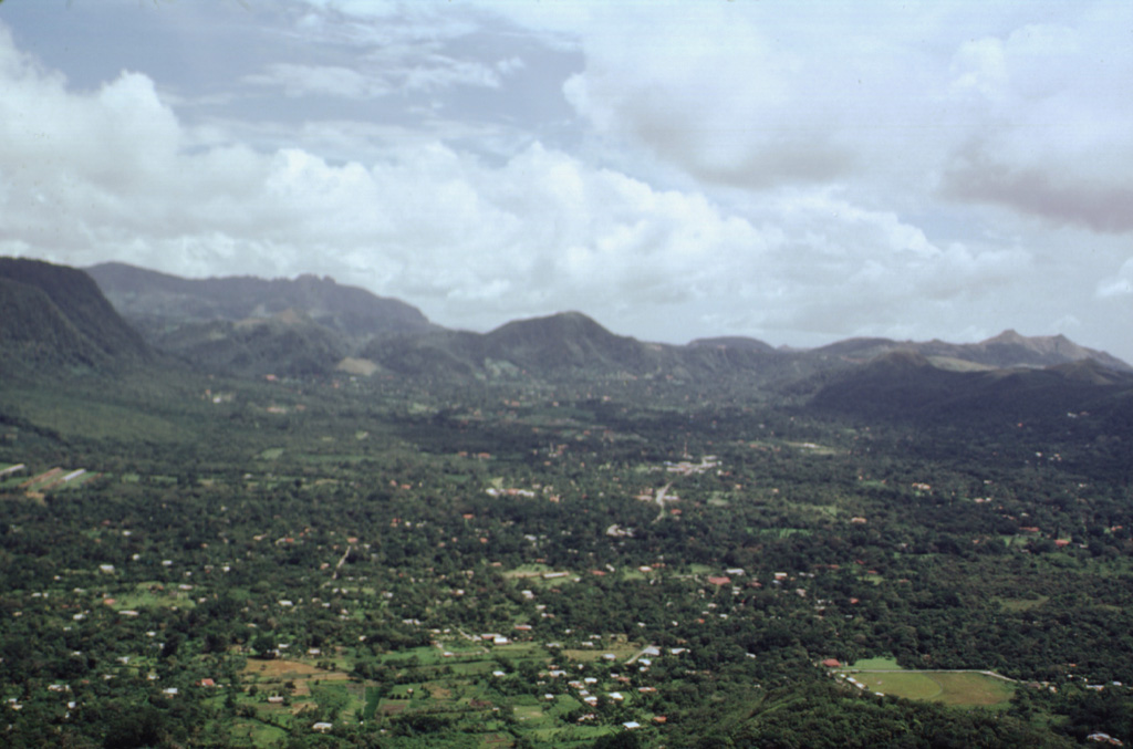 The town of El Valle occupies the El Valle de Antón caldera floor. This view looks across the 6-km-wide caldera from La India Dormida on the western rim. A lake once covered the caldera floor, contributing to large phreatoplinian eruptions during the late Pleistocene. At the far-left is Cerro Caracoral, the easternmost of three lava domes along the northern caldera margin. More recent Plinian eruptions originated from the Mata Ahogado crater, east of the caldera rim. Photo by Paul Kimberly, 1998 (Smithsonian Institution).