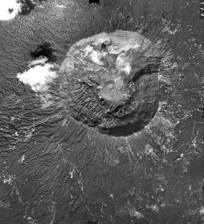 The summit of San Salvador volcano is truncated by a large steep-walled crater, Boquerón (the mouth), which formed during a major eruption producing the San Andrés Talpetate Tuff about 800 years ago.  Eruption of west-directed airfall tephra was accompanied by pyroclastic flows.  The small 30-m-high cinder cone, Boqueroncito (the little mouth) is seen in the center of the crater floor of 1.5-km-wide, 500-m-deep Boquerón and was constructed during the 1917 eruption. Aerial photo by Instituto Geográfico Nacional El Salvador, 1979.