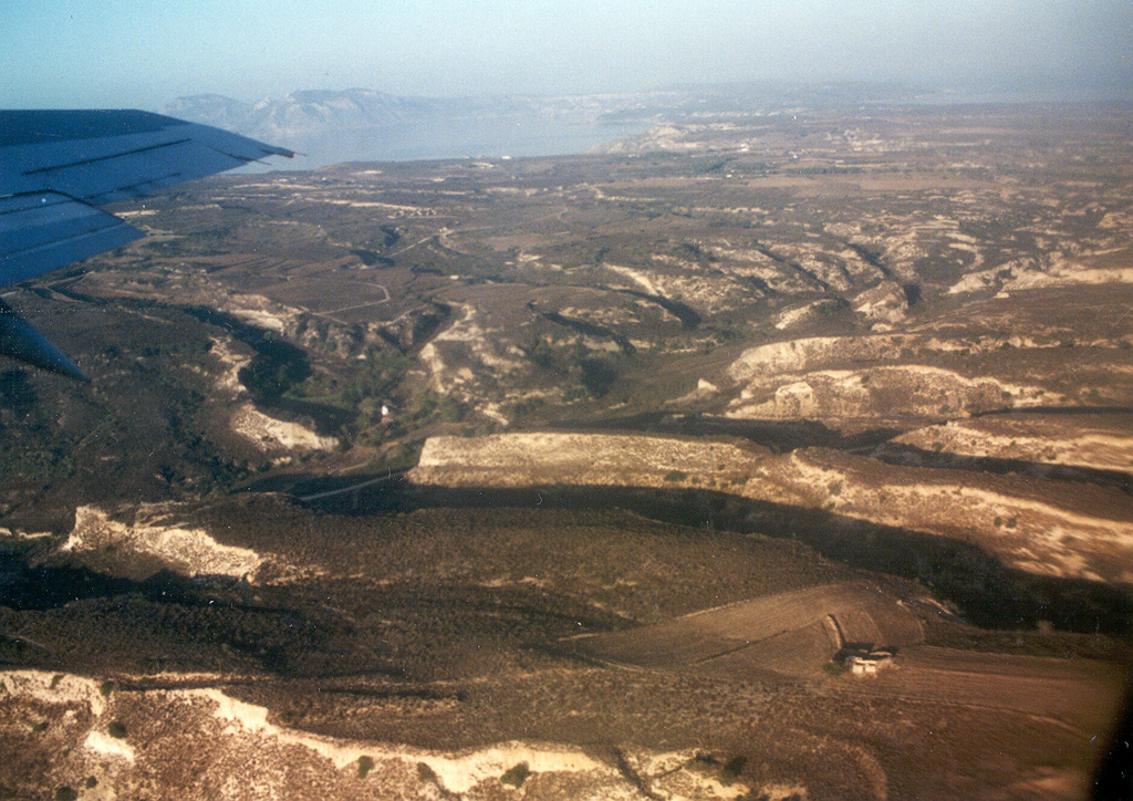 Light-colored ignimbrite deposits, eroded into mesas bounded by steep-walled valleys, cap the central part of the island of Kos. The island is dominantly non-volcanic but contains Miocene to Pleistocene volcanic centers. The Kamari caldera is of mid-Pleistocene age and contains the 1.0-0.55 million-year-old, post-caldera Zini lava dome. The widespread Kos Plateau Tuff (145,000 years old) originated from a submarine source between Kos and Nisyros islands. Several geothermal areas are found on Kos. Photo by Ichio Moriya (Kanazawa University).