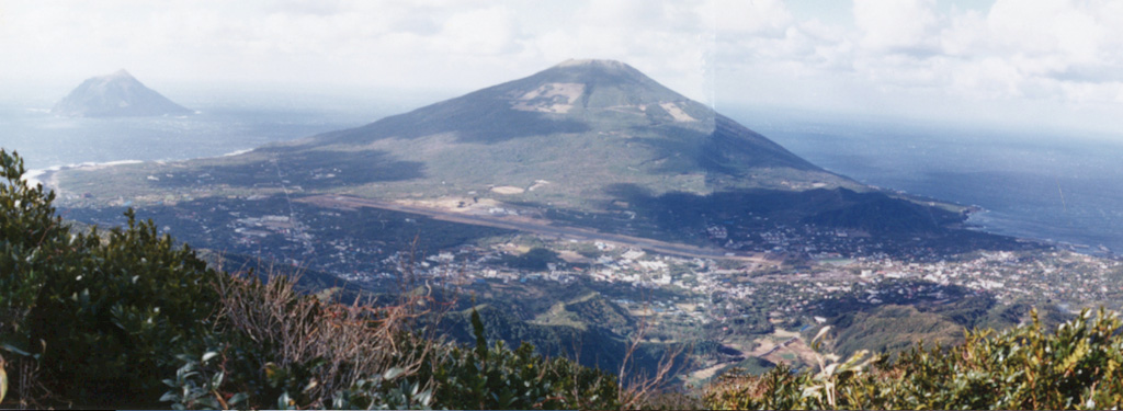 Nishiyama volcano, seen here from the older Higashiyama, forms the NW part of Hachijojima island. The island's airport and its largest town occupy the flanks. The small volcanic island of Kojima (upper left) lies several kilometers to the west. Major activity from the early Holocene until about 4,000 years ago was restricted to flank eruptions. Photo by Ichio Moriya (Kanazawa University).