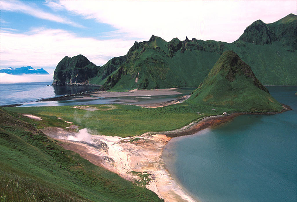 A phreatic explosion at the geothermal area to the lower left took place in July 1884. An area at the foot of the SE caldera wall containing fumaroles (to the lower left of this photo) was a sacred place to 18th to 19th century Ainu people. The caldera rim opens to the south with a 300-m-wide gap that allows sea water to flood the caldera floor. The peak to the left-center is one of two older lava domes connected by a grass-mantled sand bar to the SE caldera wall. Ketoi Island (right) is visible in the distance to the SW. Photo by Yoshihiro Ishizuka, 2000 (Hokkaido University).