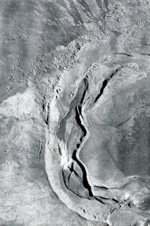 A dramatic sinuous N-S-trending ridge extends across the western side of the summit caldera of Sierra Negra volcano, forming the border of a graben lying between it and the caldera wall to the left.  Volcán Azufre, the largest fumarolic area in the Galápagos Islands, is located in this part of the 7 x 10.5 km wide caldera.  An arcuate line of small vents parallel to the caldera wall were produced by eruptions from circumferential fissures parallel to the caldera walls and fed lava flows that primarily traveled down the outer flanks of the volcano. Photo by U.S. Air Force, 1946