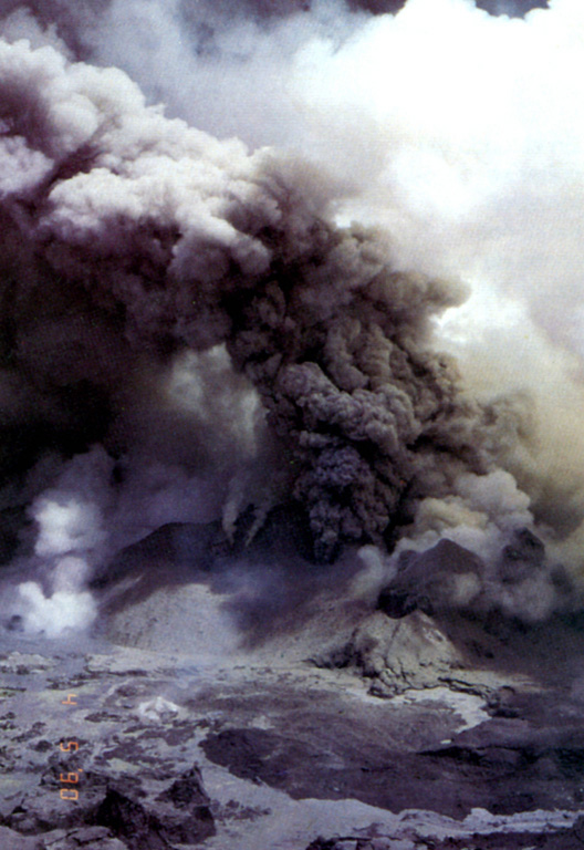 Ash plumes rise above vents in the Poás summit crater on 4 May 1990, near the end of an eruptive period that began in June 1987. At the time of this photo the crater lake had shrunk substantially to only several centimeters deep that fluctuated slightly with changes in rainfall recharge. Lake temperatures were over 72°C (measured by infrared thermometer), and small hot springs around the lake had temperatures of 85°C. Minor explosive eruptions continued into the following month.  Photo by Jorge Barquero, 1990 (Universidad Nacional Costa Rica).