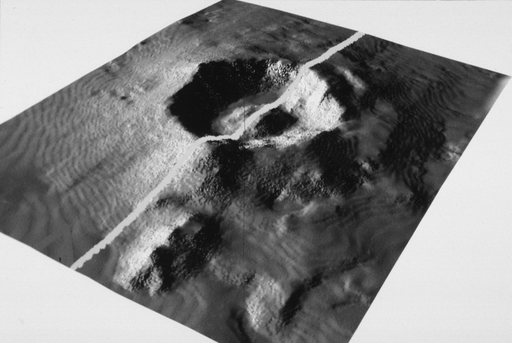 The submarine topography of the 6-7 km Myojin Knoll caldera is seen in this SeaBeam image viewed from the SW. The white line marks the E-W track of the survey vessel. A voluminous deposit of coarse pumice from the caldera-forming eruption mantles the caldera rim and its outer flanks. A post-caldera lava dome rises 250 m above the caldera floor. Image by Fumitoshi Murakami (Geological Survey of Japan, courtesy of Richard Fiske, Smithsonian Institution).